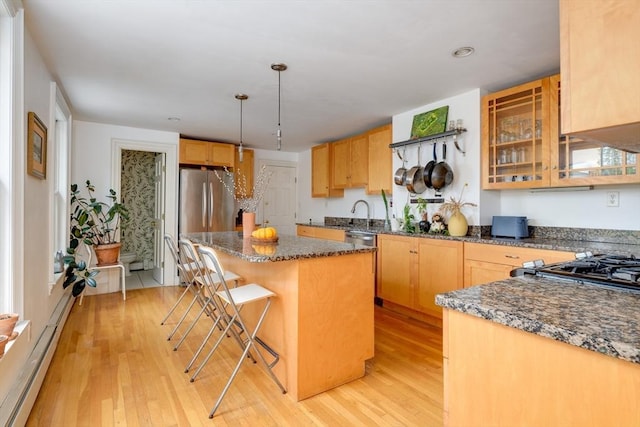 46 Bigelow St Unit 3, Cambridge, MA 02139 - kitchen with appliances with stainless steel finishes, baseboard heating, light wood finished floors, a center island, and a breakfast bar