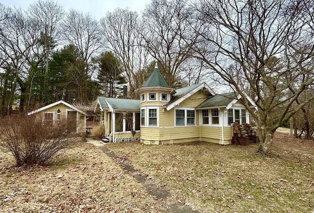 back of house with covered porch, a chimney, and a shingled roof