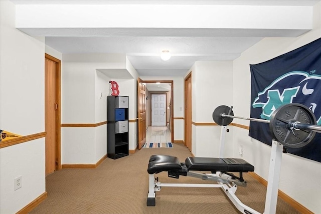 exercise area featuring light colored carpet and baseboards