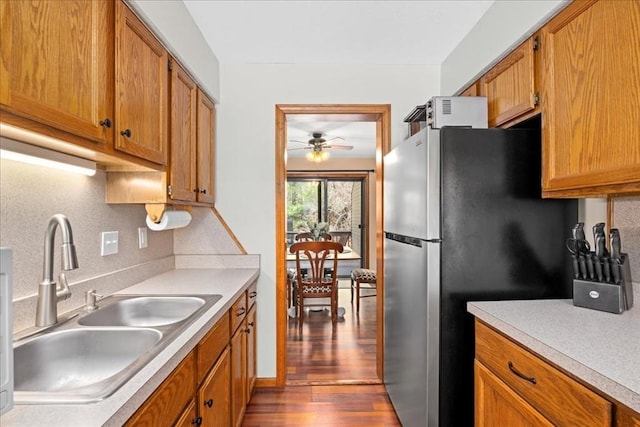 kitchen featuring decorative backsplash, freestanding refrigerator, a ceiling fan, and a sink