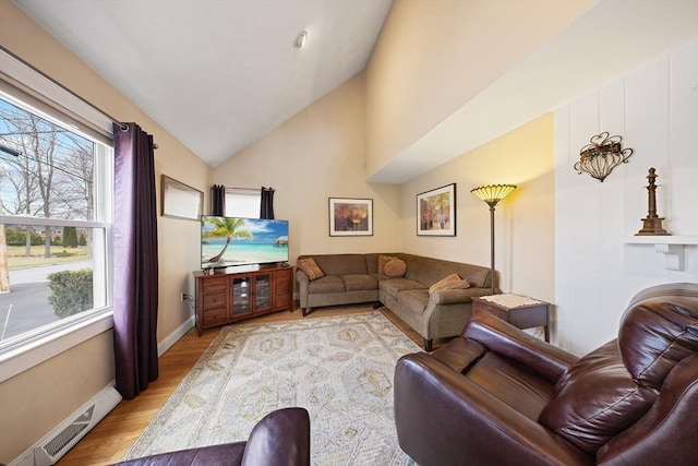 living area with light wood finished floors, vaulted ceiling, baseboards, and visible vents