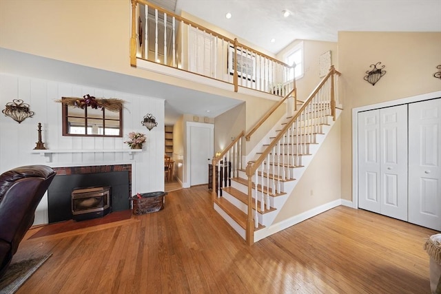interior space featuring baseboards, wood finished floors, high vaulted ceiling, and a wood stove