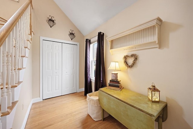 bedroom featuring lofted ceiling, light wood-style flooring, baseboards, and a closet