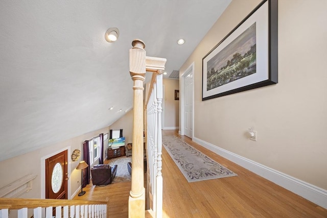 hallway with baseboards, lofted ceiling, and wood finished floors