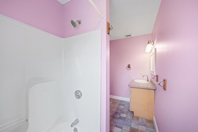 full bath featuring visible vents, vanity, tub / shower combination, stone finish flooring, and baseboards