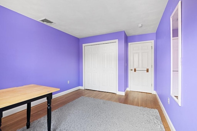 bedroom featuring visible vents, wood finished floors, baseboards, and a closet