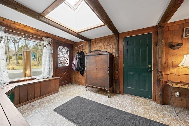foyer entrance featuring a skylight, wooden walls, and beam ceiling