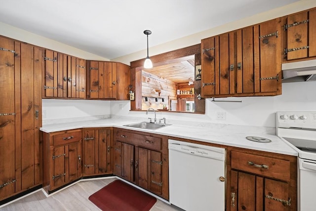 kitchen featuring a sink, white appliances, brown cabinetry, light countertops, and under cabinet range hood