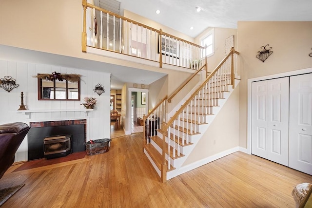 interior space with high vaulted ceiling, stairs, wood finished floors, a wood stove, and baseboards