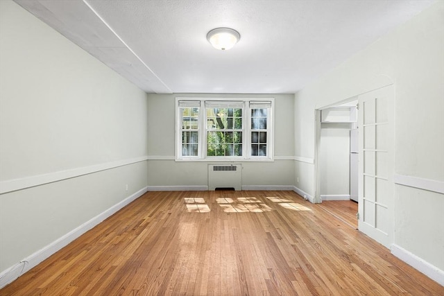 interior space featuring baseboards, radiator, and light wood-style floors