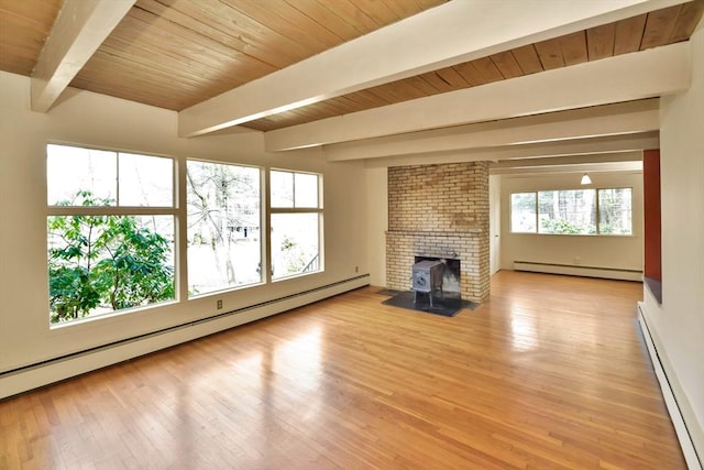 unfurnished living room featuring baseboard heating, a baseboard radiator, a wood stove, and light wood-style flooring