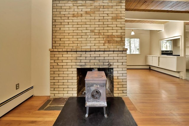 room details with baseboard heating, a wood stove, beam ceiling, wood ceiling, and wood finished floors