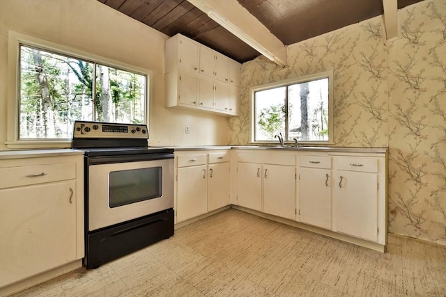 kitchen with plenty of natural light, electric stove, beamed ceiling, wallpapered walls, and light floors