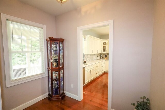 corridor featuring baseboards and dark wood-style flooring