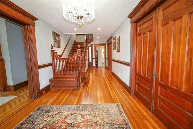 hall with stairs, baseboards, light wood finished floors, a notable chandelier, and recessed lighting