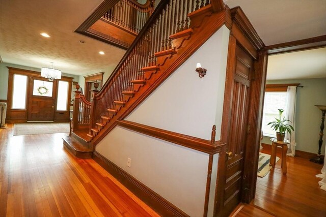 entrance foyer featuring wood finished floors, stairway, baseboards, an inviting chandelier, and recessed lighting
