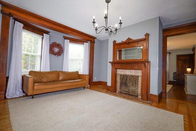 living room with baseboards, a chandelier, and a tile fireplace