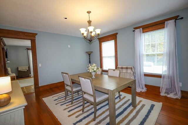 dining space featuring baseboards, a notable chandelier, and wood finished floors