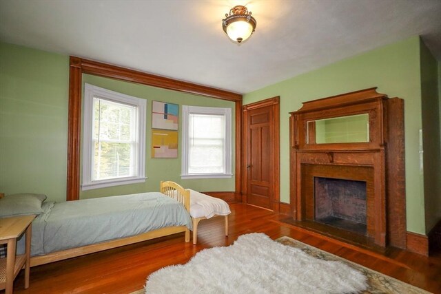bedroom with wood finished floors and a fireplace