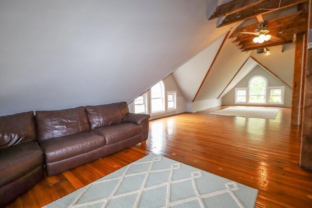 living area with a healthy amount of sunlight, ceiling fan, wood-type flooring, and vaulted ceiling