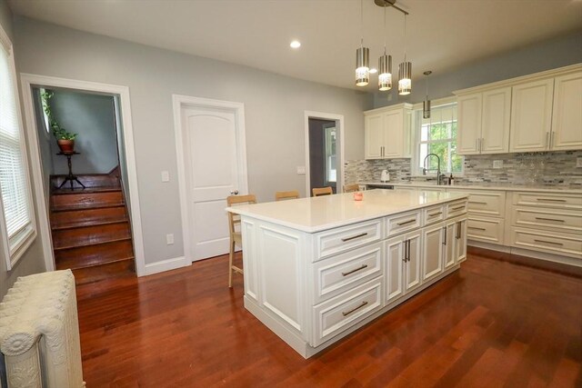 kitchen featuring light countertops, decorative backsplash, radiator, and dark wood-type flooring
