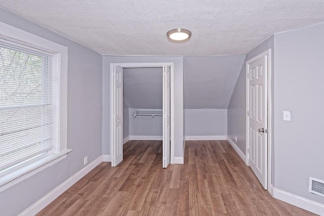 additional living space featuring wood finished floors, a textured ceiling, and baseboards