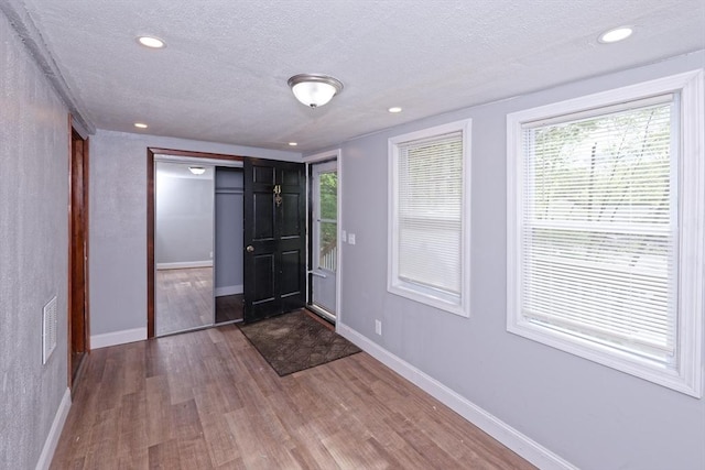 entrance foyer featuring a textured ceiling, wood finished floors, baseboards, and recessed lighting