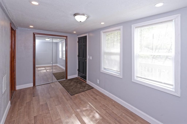 foyer entrance with wood finished floors, baseboards, recessed lighting, and a textured ceiling