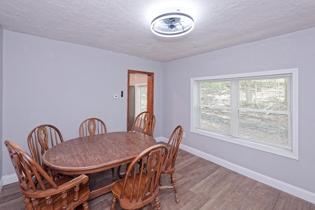 dining room featuring wood finished floors, baseboards, and a textured ceiling