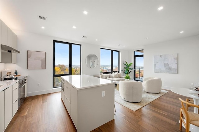 kitchen with a kitchen island, white cabinets, light wood-type flooring, and plenty of natural light