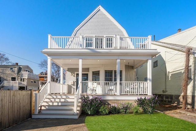 view of front of house with a porch, a balcony, fence, and a gambrel roof