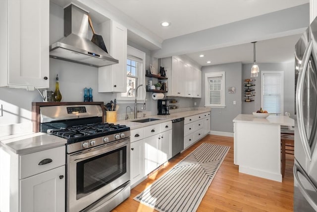 kitchen with a sink, stainless steel appliances, wall chimney exhaust hood, and light countertops