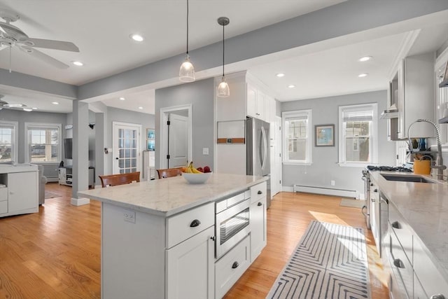 kitchen with light stone counters, light wood finished floors, recessed lighting, white cabinets, and baseboard heating