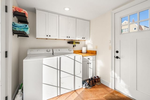 washroom featuring baseboards, cabinet space, wood finished floors, and washing machine and clothes dryer