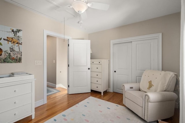 living area featuring baseboards, light wood-style floors, attic access, and a ceiling fan