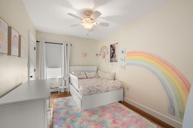 bedroom featuring a ceiling fan, wood finished floors, baseboards, and a baseboard radiator