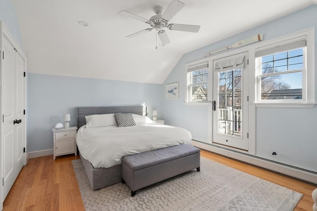 bedroom with a ceiling fan, access to outside, wood finished floors, a baseboard radiator, and vaulted ceiling