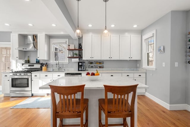 kitchen featuring a sink, stainless steel appliances, white cabinetry, and wall chimney range hood