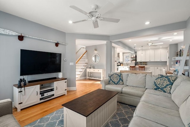 living area featuring light wood-style flooring, a ceiling fan, recessed lighting, baseboards, and stairs