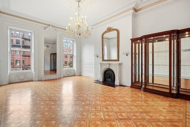 unfurnished living room with a notable chandelier, light parquet floors, and ornamental molding