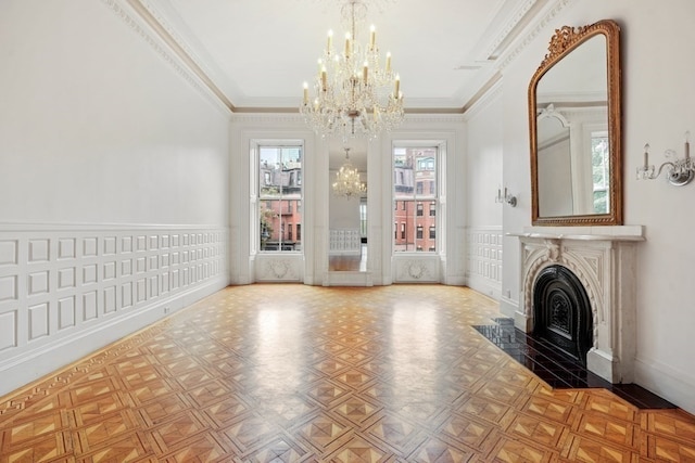 unfurnished living room with crown molding, light parquet flooring, and an inviting chandelier