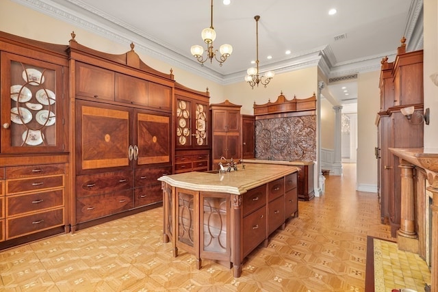 kitchen featuring hanging light fixtures, light stone counters, an island with sink, a notable chandelier, and sink