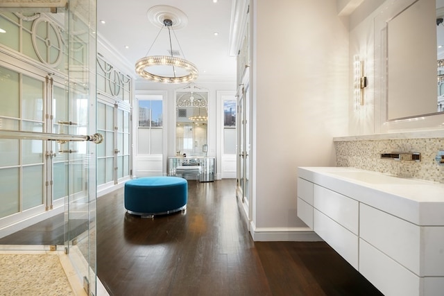 bathroom with a shower with shower door, vanity, tasteful backsplash, wood-type flooring, and crown molding