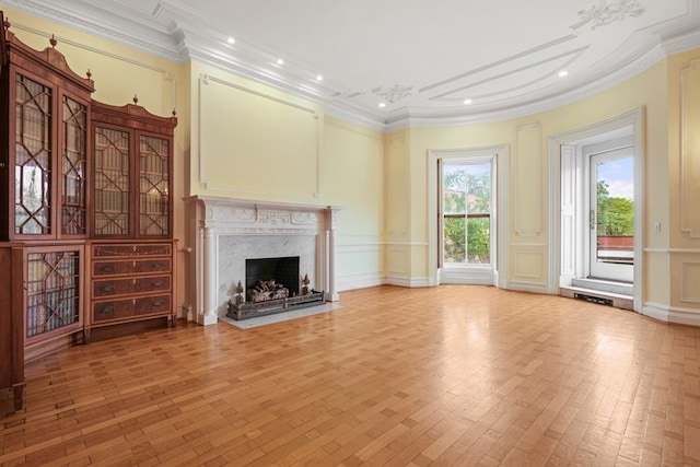 unfurnished living room featuring a high end fireplace, ornamental molding, and light hardwood / wood-style flooring