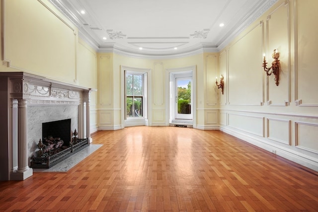 unfurnished living room with a premium fireplace, crown molding, and light hardwood / wood-style flooring