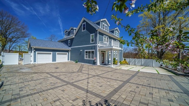 view of front facade featuring a gate, a balcony, fence, and an attached garage
