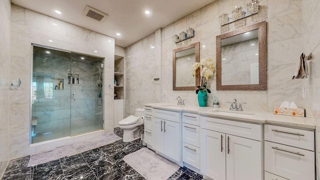 bathroom featuring tile walls, toilet, a shower stall, marble tiled floors, and double vanity