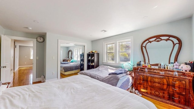bedroom with wood finished floors, baseboards, and a closet