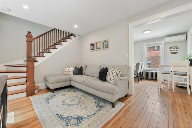 475 E St, Dedham, MA 02026 - living room featuring radiator heating unit, a wall unit AC, light wood-style floors, stairs, and recessed lighting