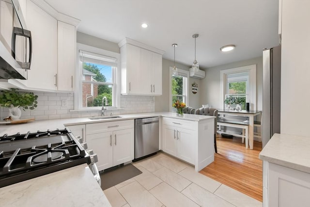 475 E St, Dedham, MA 02026 - kitchen featuring stainless steel appliances, a sink, white cabinetry, decorative backsplash, and a peninsula